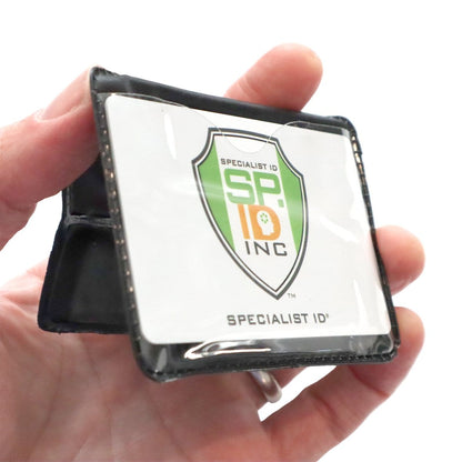 A hand holds a black Horizontal Magnetic Badge Holder (P/N 1835-1050) with a clear vinyl front, displaying a Specialist ID Inc. card featuring a green and orange logo.
