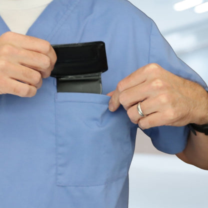 A person wearing blue scrubs places a black wallet or phone into the chest pocket of their Horizontal Magnetic Badge Holder (P/N 1835-1050).