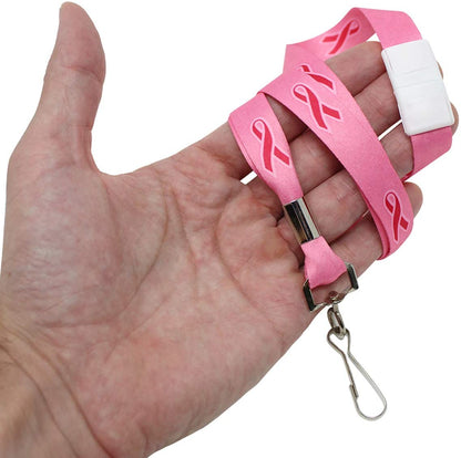 A hand holds a Pink Ribbon Awareness Wide Flat Breakaway Lanyard w/ Swivel Hook 2138-5286 with breast cancer awareness ribbons and a metal clip.