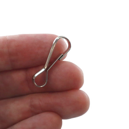 A hand holding a Small Metal J Hook Spring Clip - 1 1/4" for DIY Lanyards & Keychains (6920-2350) with a simple, bent-wire design, perfect for attaching ID cards or badge holders.