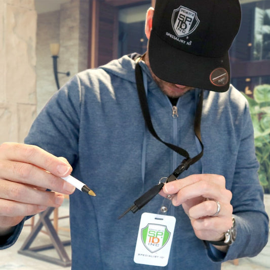 Person using a pen with black badge lanyard and detachable pen holder near a sample ID card