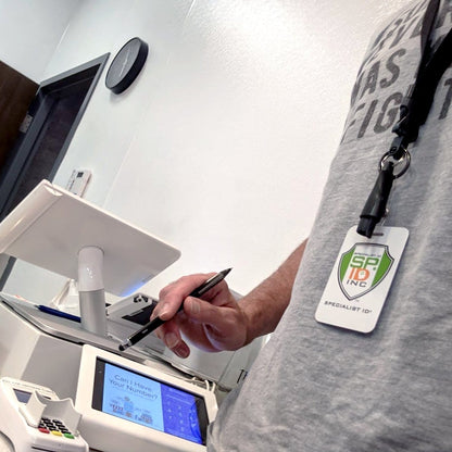 Person holding a Lanyard with Pen and ID Badge Holder - All in One Neck Lanyards (SPID-2380), standing next to a machine with a screen displaying "Can I Have Your Number?" Their breakaway lanyard shows a badge labeled "SPECIALIST / SPEC INC.