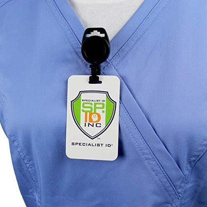 A person wearing blue scrubs has an MRI Safe Badge Reel - Non-Ferrous Metal Retractable Badge Clips with No Twist ID Holder Clip for Imaging Room Techs & Nurses clipped to their chest, displaying a white ID card with the logo and text "Specialist ID Inc.