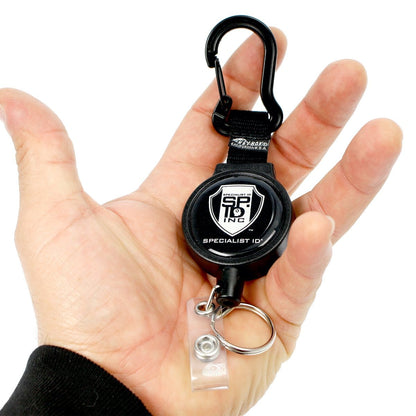 Hand holding a Heavy Duty SPID Key-Bak Mid-Size Carabiner Retractable Badge Reel with Card Strap & Key Ring (SPID-3330) with a durable Kevlar cord and carabiner clip attachment, featuring the "Specialist ID" logo on it.