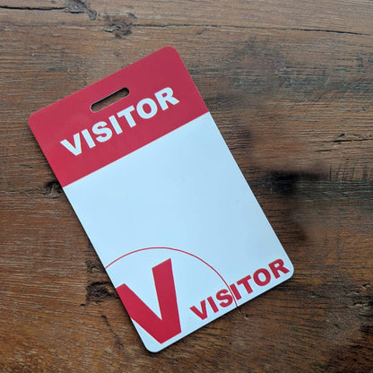 A Visitor Badges with Lanyard - Secure Guest ID Passes for Events and Offices with a red and white design lies on a wooden surface. Sold by Specialist ID.