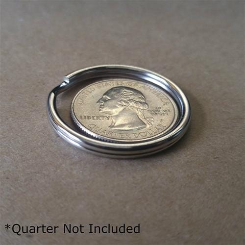 A metal ring holder, made from heat treated steel, is shown on a surface with a quarter placed inside for scale. The text "*Quarter Not Included" is displayed in the bottom left corner. Perfect for keychain accessories and split rings like 25 Premium Extra Large 1 1/4" Split Rings (SPID-9240).