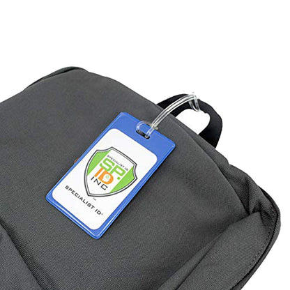 A grey backpack with a blue-tagged ID card attached to the handle, displaying a logo that reads "SP-10 INC Specialist ID," features a Color Coded Backpack ID Tags with Loop - Semi Rigid Holds a Business Card or Included Identification Card (1845-200X) for added durability.