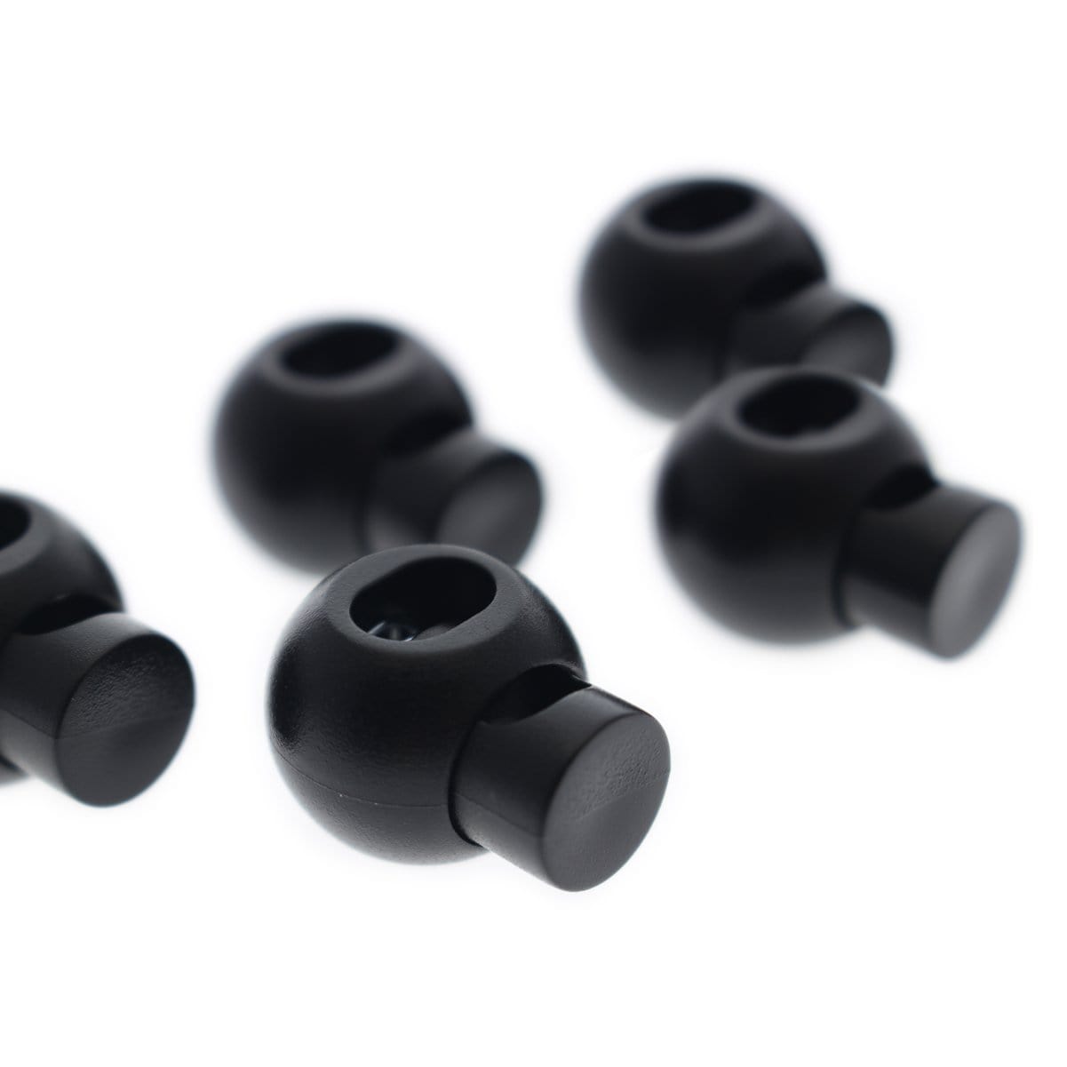 Four black interchangeable earbud tips and two Adjustable Cord Lock - Round Ball Style - Single Hole End Toggles for DIY Projects (2135-4001) are arranged on a white background.