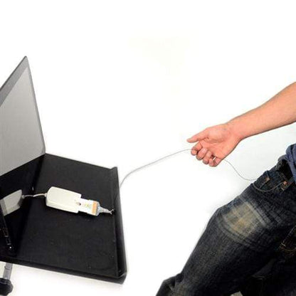 A person is holding a cable connected to a laptop with an external device attached. The laptop screen is black, and the person is partially visible, wearing a blue shirt and jeans. Clipped to their waistband is a Lock-A-Reel Self Locking PIV Card Reel, slightly swinging as they move.