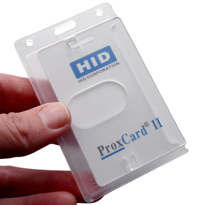 A hand holds a Vertical 70 - 90 Mil ProxCard II / Thick HID Proximity Card Holder (SPID-PROX-V) in a transparent HID Proximity Card Holder, showing the HID Corporation logo on the white card.