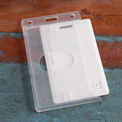 Close-up of a Vertical 70 - 90 Mil ProxCard II / Thick HID Proximity Card Holder (SPID-PROX-V) inside a transparent plastic holder, placed on a distressed wooden surface.