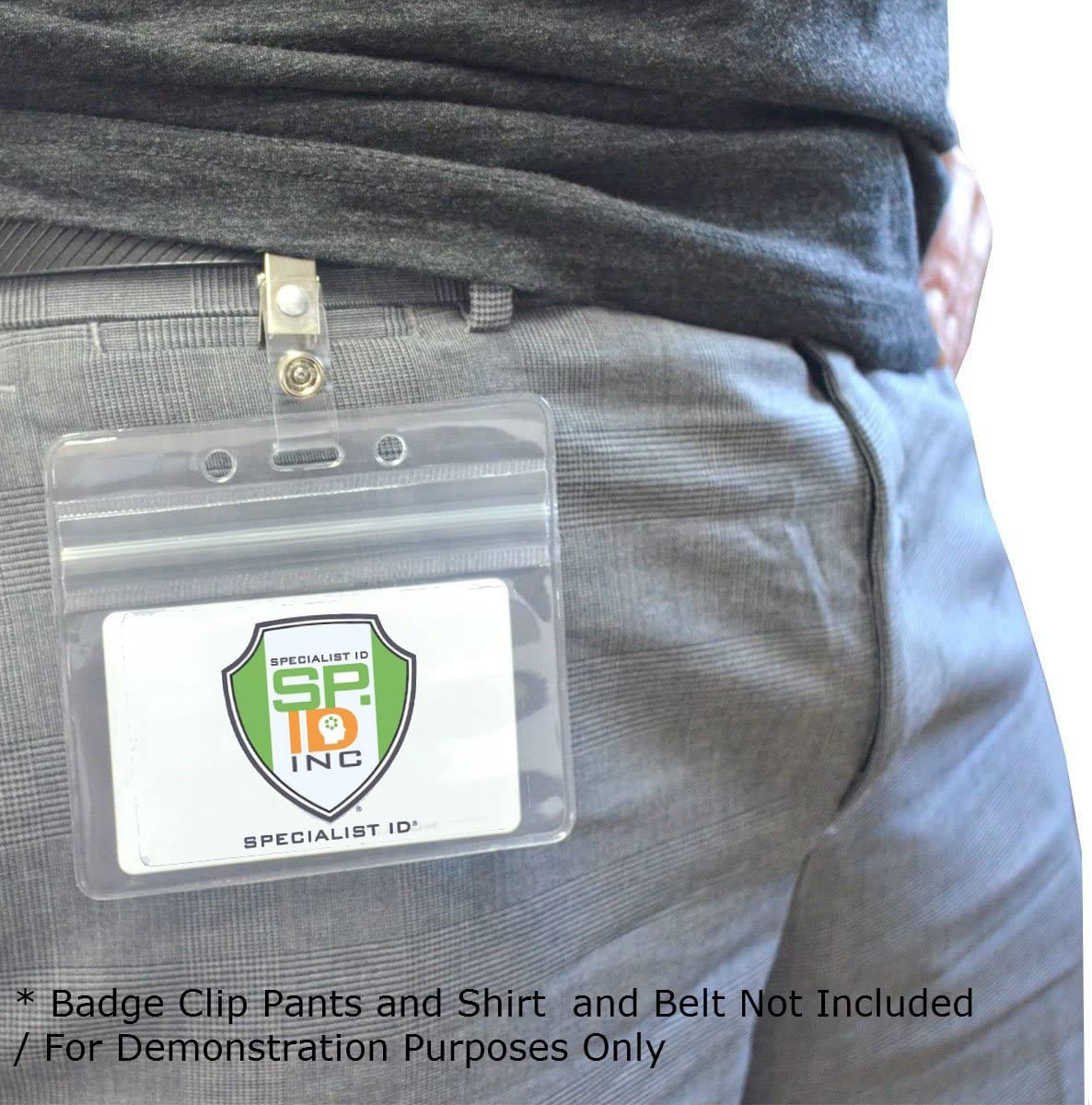 Close-up of a person wearing gray pants with a Horizontal Vinyl Badge Holder with Zipper Top (506-ZHOS-CLR) clipped to the waistband. The badge has a logo and the text "SPECIALIST ID INC." Text at the bottom clarifies that the clip, pants, and belt are not included in the sale, ensuring exceptional ID card protection.