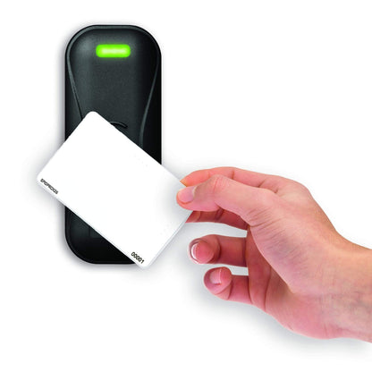 A hand holds a white SPIDprox HID Compatible ISO Prox Card near a black proximity card reader with a green light on, highlighting the efficiency of modern access control systems. Sold by Specialist ID.
