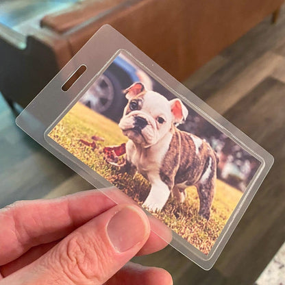 A person holds a **7 Mil Medium Duty Laminating Pouch for 2.5" x 4.25" Luggage Tags or ID with Vertical Slot Hole** featuring a photo of a young bulldog standing on grass, which could easily be turned into a creative luggage tag.