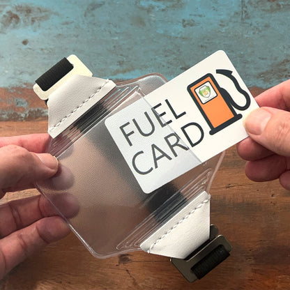 A person holds a Clear Fuel Card Holder for Visor with Elastic Band and a clear case with white straps designed to hold the card. Sold by Specialist ID.